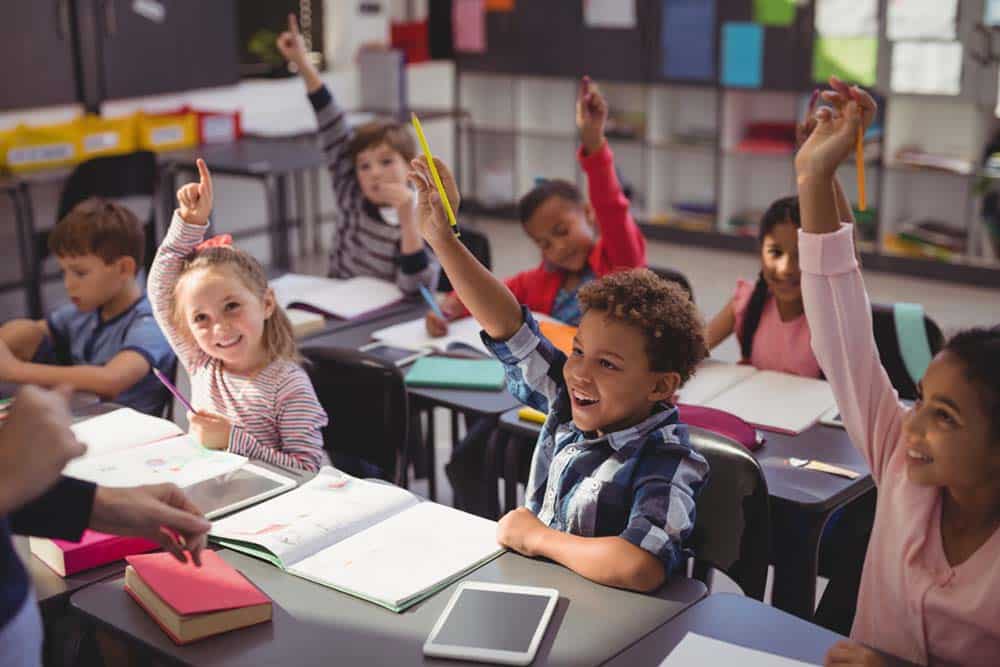 Schoolkids raising their hands in classroom vance school liaison